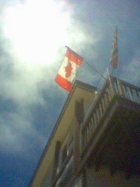 a large canadian flag is flying on the corner of a tall building