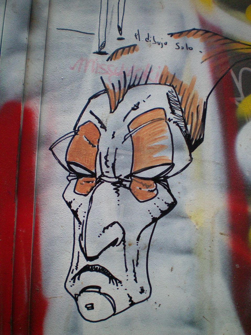 a graffiti wall with the face of a man's head and a large feather
