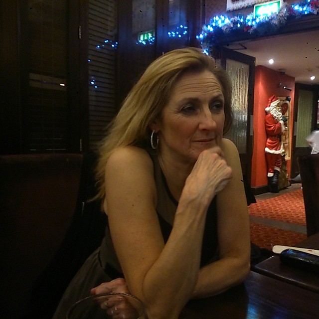 a woman sits on a brown table and looks off into the distance