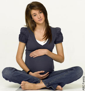 a pregnant woman is sitting on the floor and showing her stomach