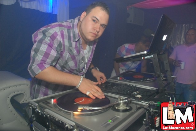a man wearing a watch around his neck playing a dj's turntable
