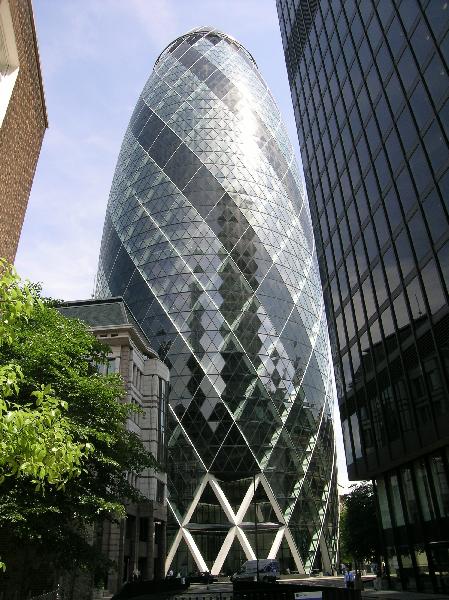 a large glass building is next to a few buildings