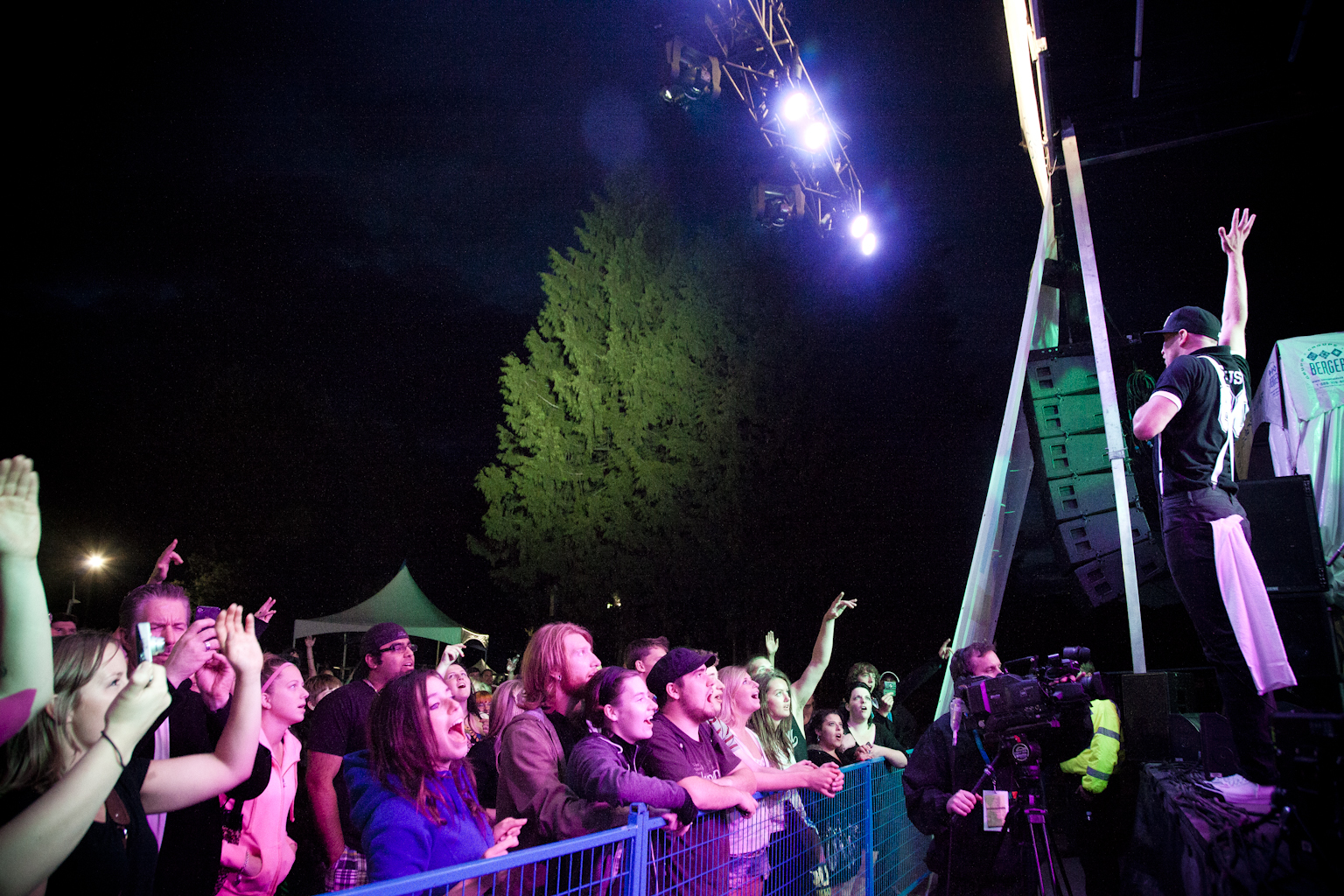 many people are watching a concert while there is a man on a stage in the center of a crowd