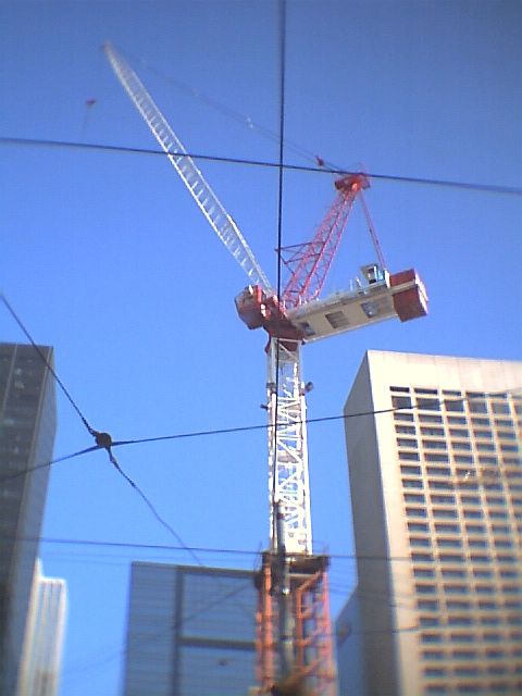 a crane on top of a building near other buildings