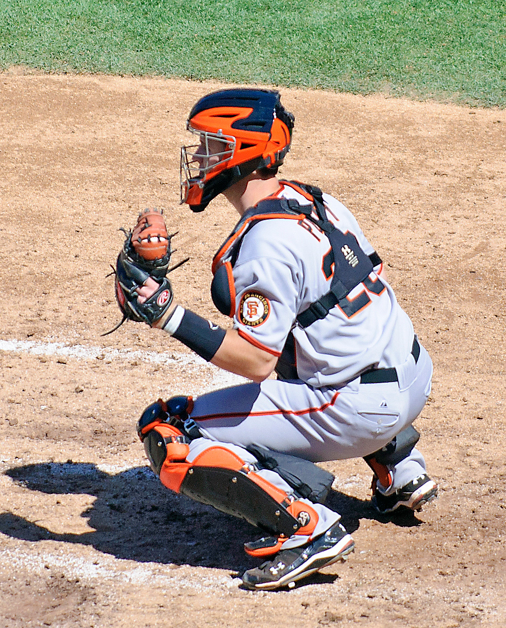 a catcher wearing red gloves stands in the dirt