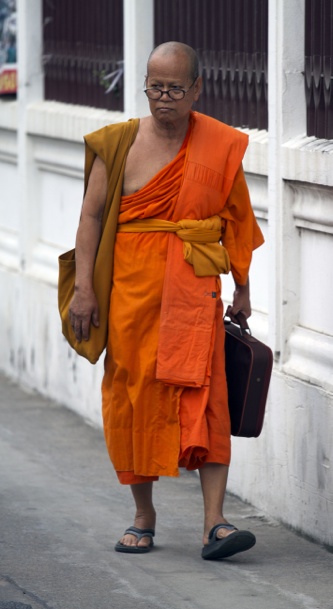 a person in an orange robe with suitcases