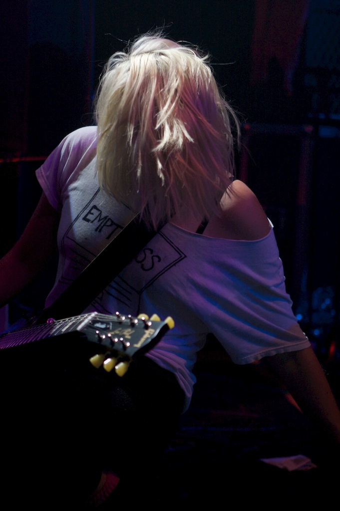 a woman with blonde hair is playing an electric guitar