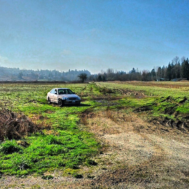 a white car parked on the side of a dirt road