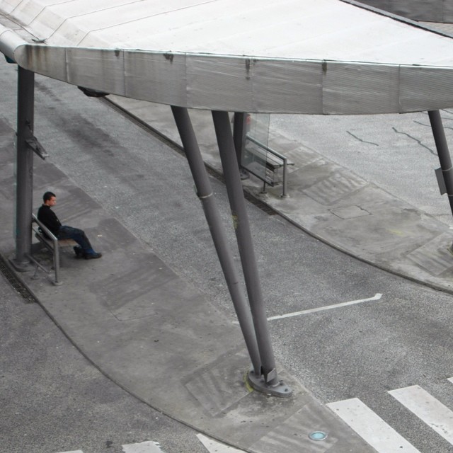 a man sitting on a bench next to an empty street