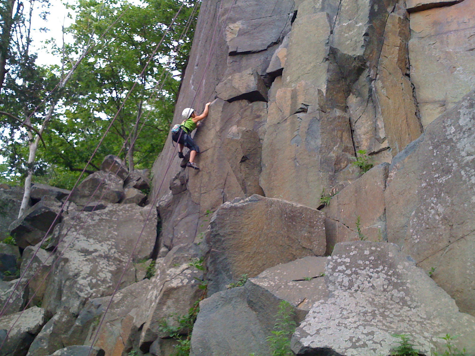 a man climbs up the side of a large rock