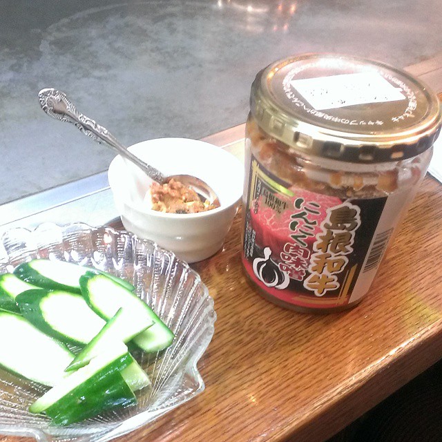 this is a glass bowl with sliced onions, green peppers and an opened jar of food on a table