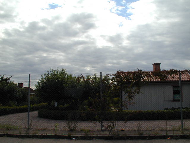 a grey sky and clouds over an older looking house