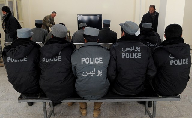 police officers in full jackets sitting on bench in a room