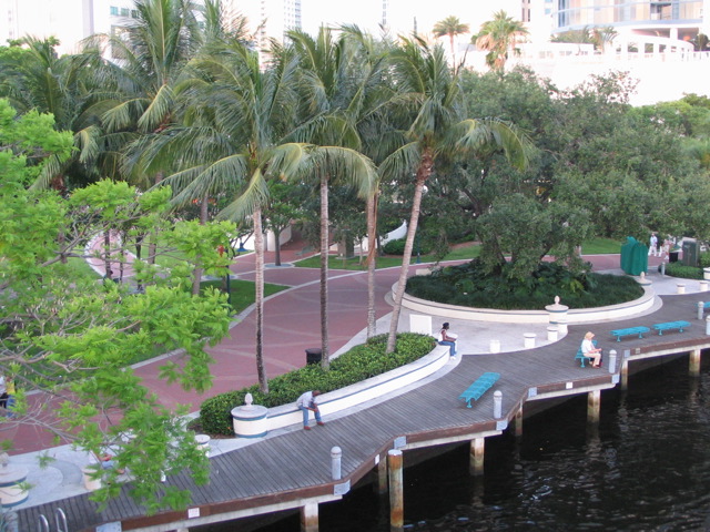 a wooden pier surrounded by palm trees on the side of a river