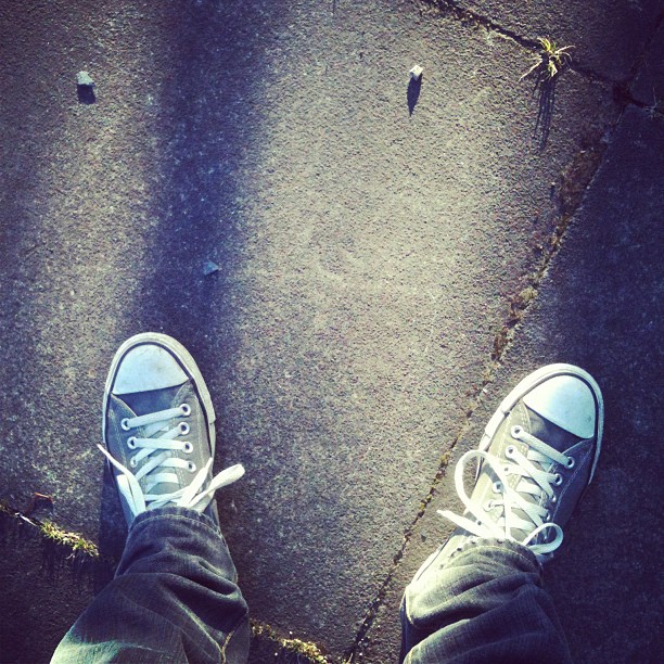 a person with converses is standing near a street