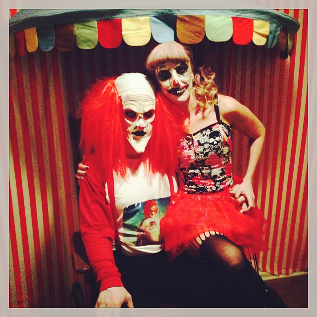 two people dressed as clowns sitting in a booth