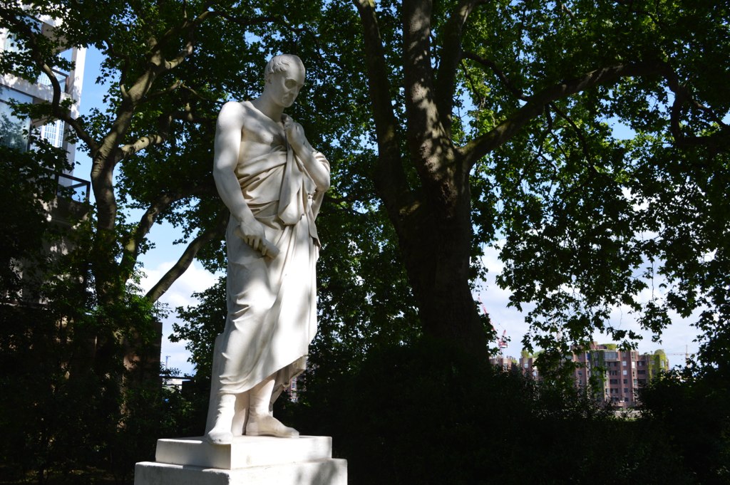 a statue stands in front of the trees