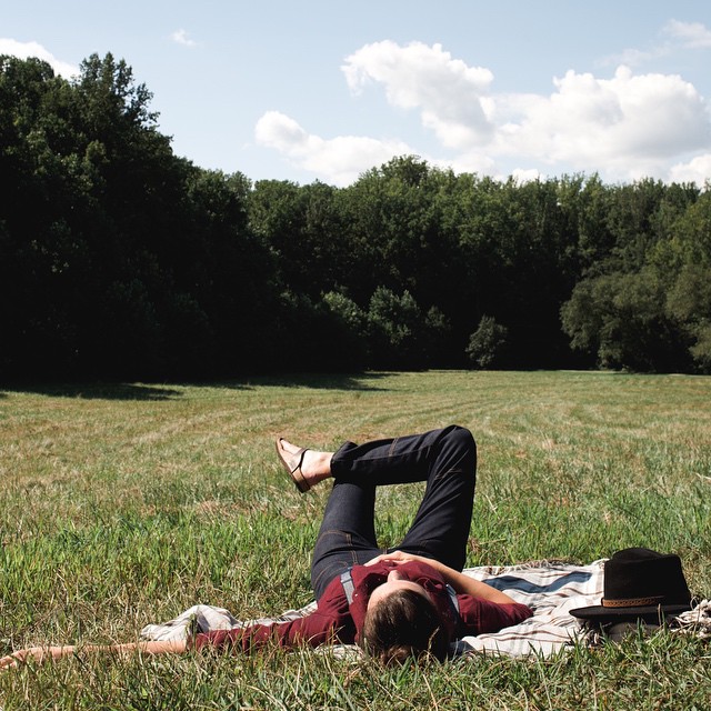 a man laying in the grass while his legs are still hanging out