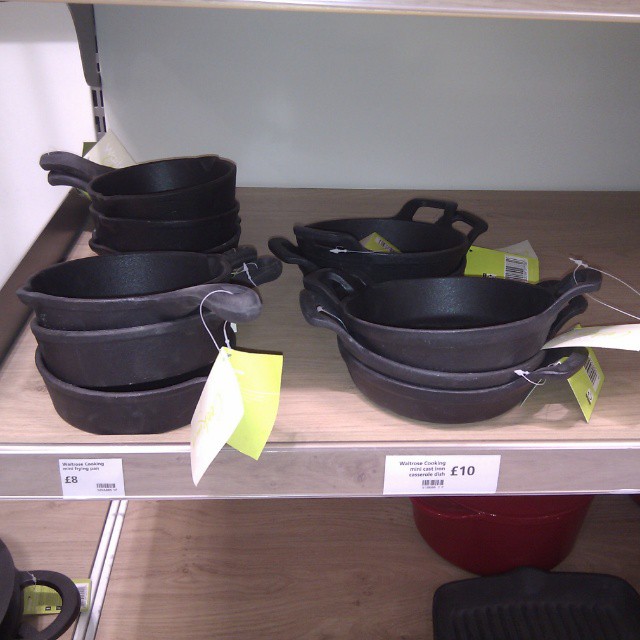 pans lined up on a shelf with one on the bottom
