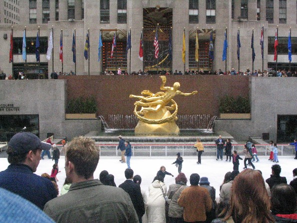 group of people gathered around ice skating in front of building