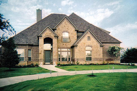a house sits in front of a green yard with grass and shrubs
