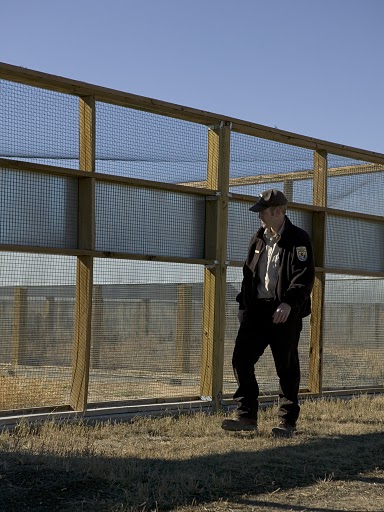 a man is standing in front of some fence