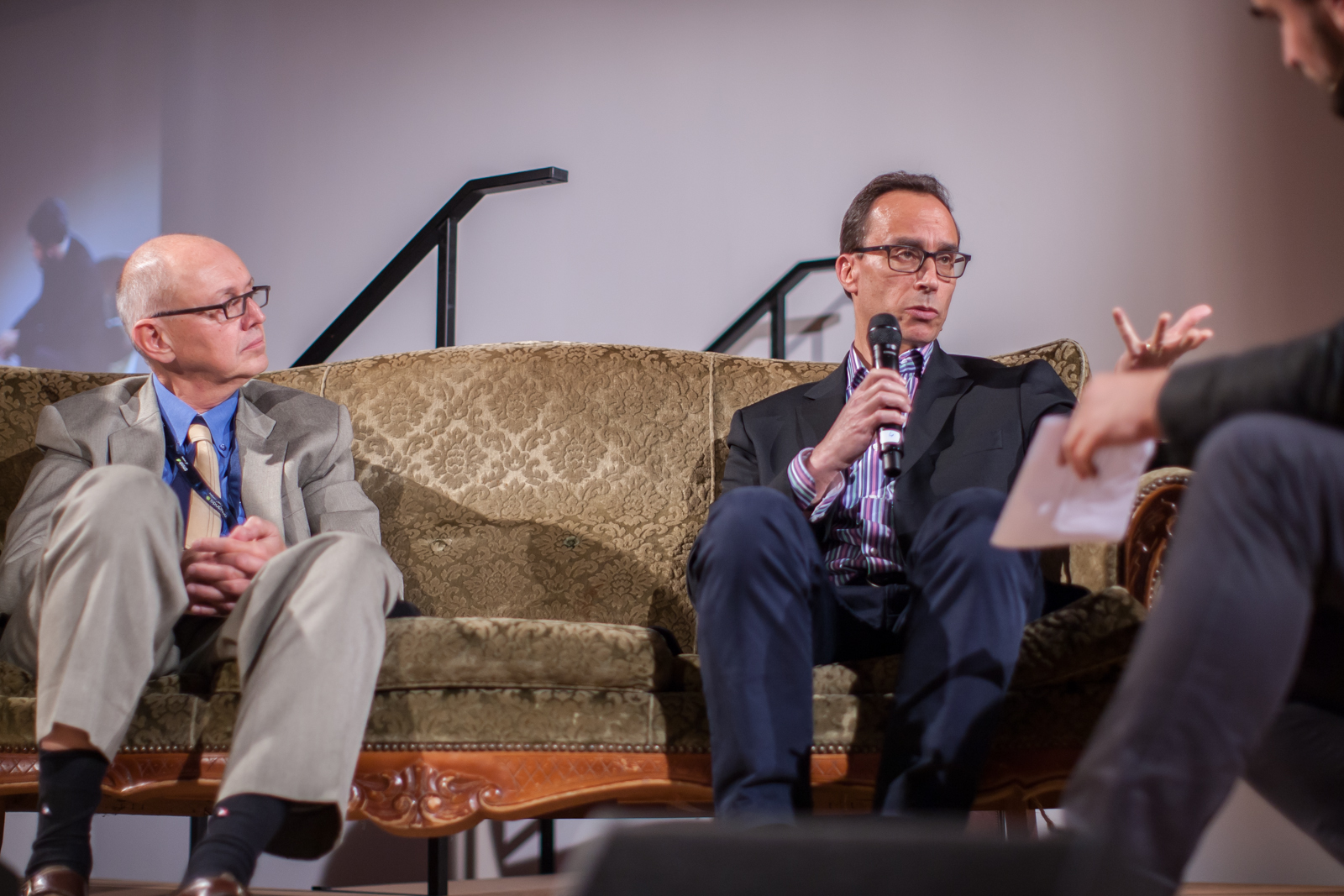 two men sitting on a couch next to each other