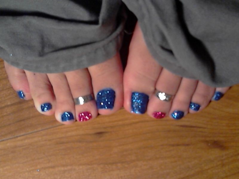 a close up of two foot with blue and red polish