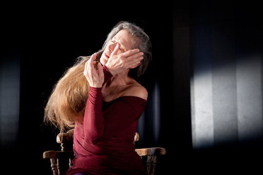 a woman covers her face as she sits in a chair