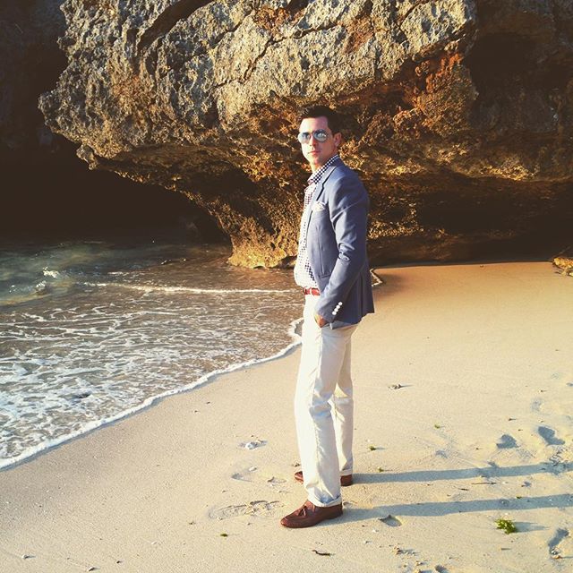 a man standing on a beach next to a large cliff