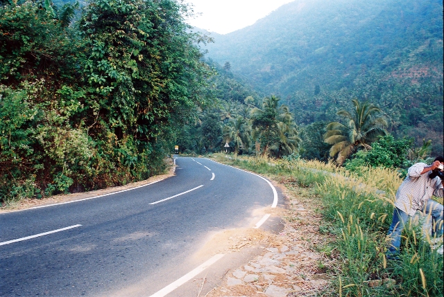 a man on a road taking pictures of the mountain