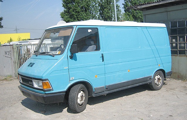 a small blue van parked on the side of the road
