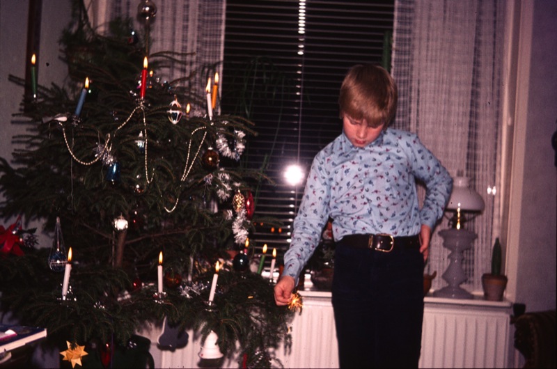 boy is dressed for the holidays in front of a christmas tree