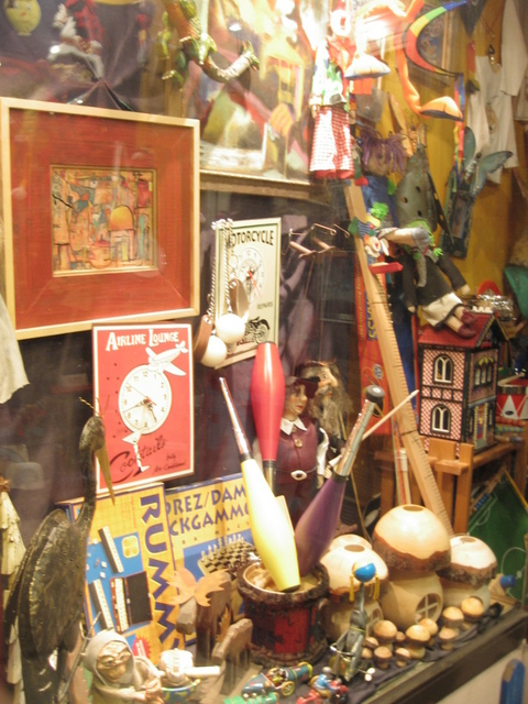 an assortment of items and art are displayed in the shop window