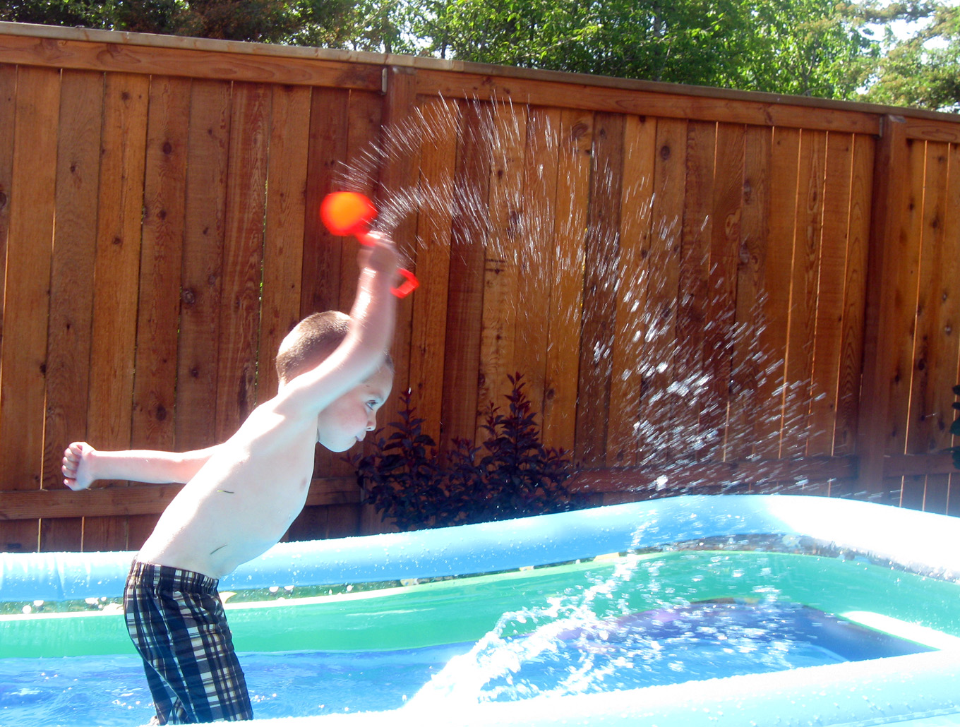 a small boy splashes water from an inflatable pool