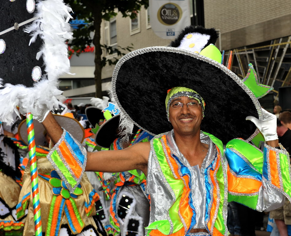 man wearing a hat and costume while holding a feather fan
