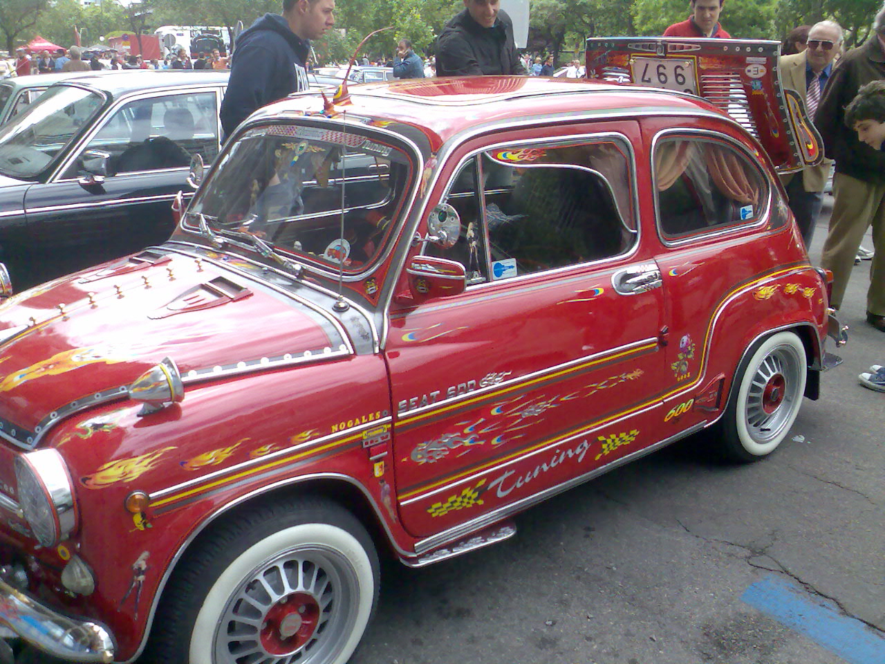 several people standing by a red vintage car