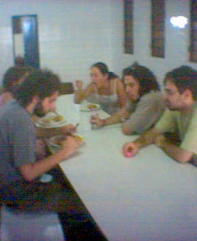 a group of people sitting around a table eating and drinking