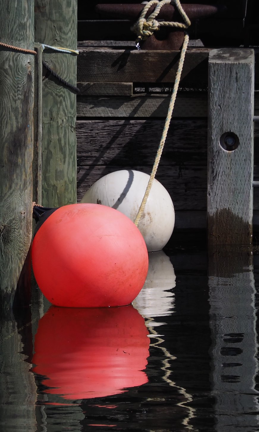 three large red and white buoys sitting in water