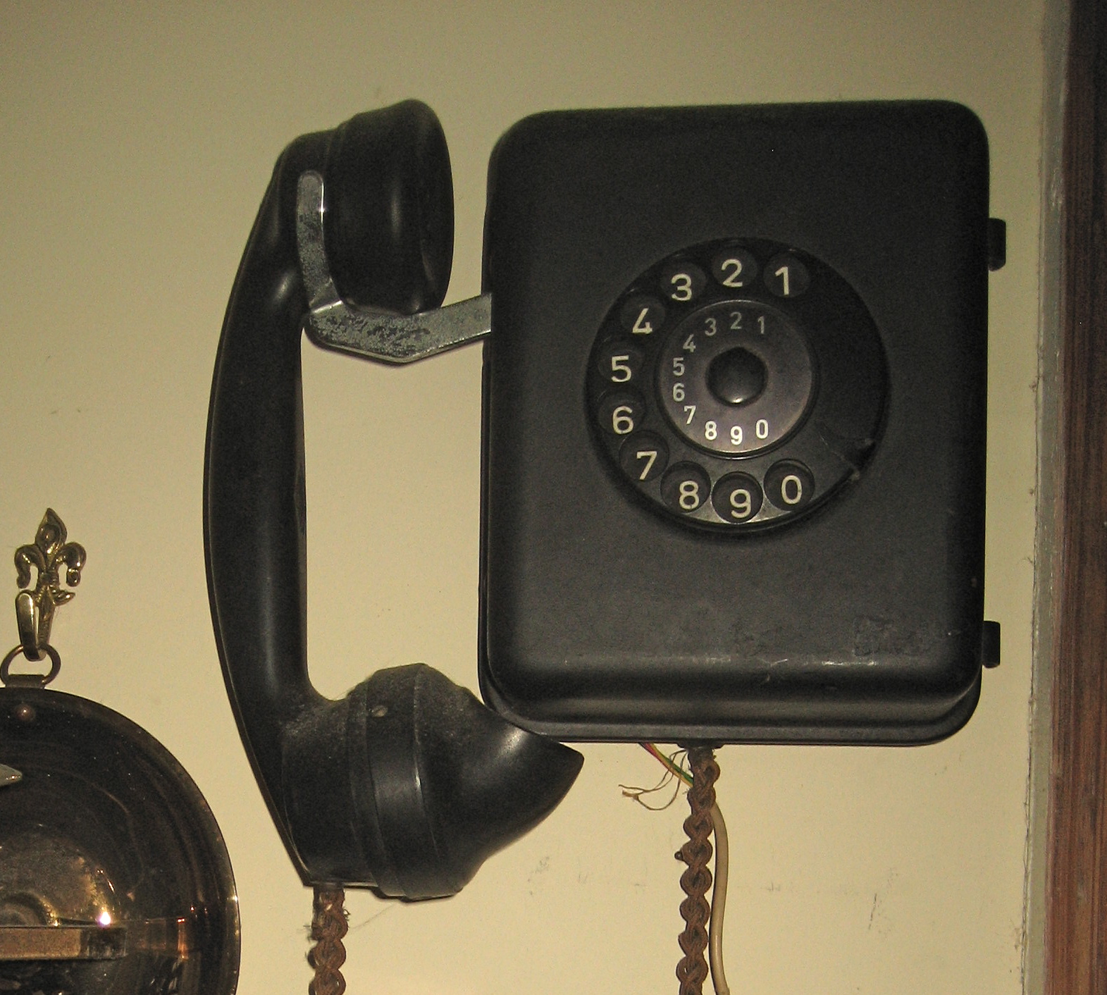 an old fashioned telephone on the wall with other old phone and bells