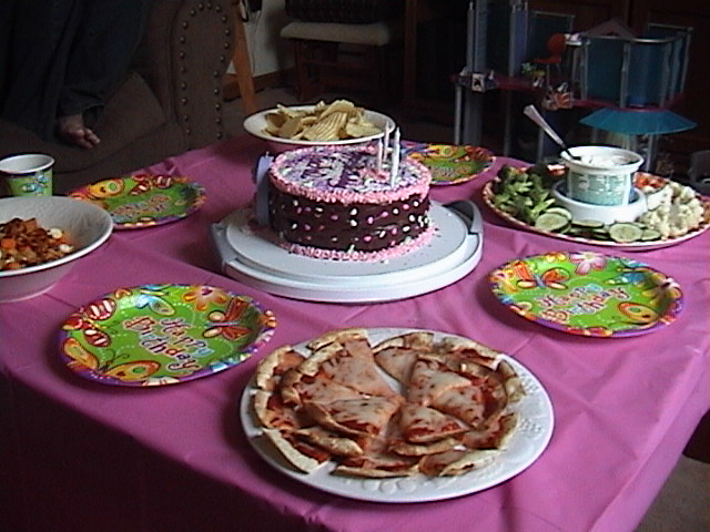 several plates with different foods and sauces, on a table with pink cloth