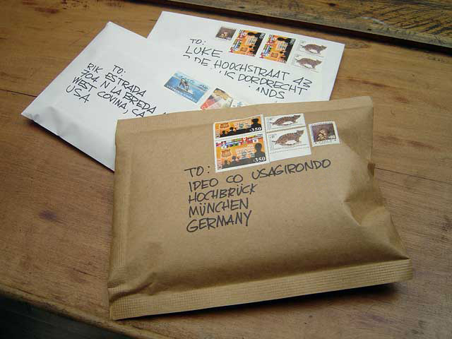 three letters with stamps on them are placed next to a bag