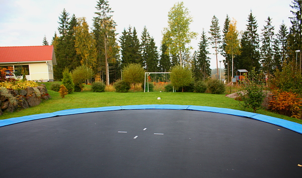 a backyard with a blue trampoline and two s playing