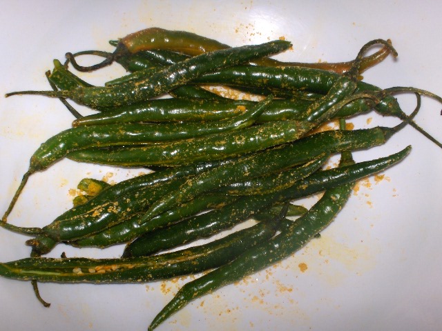 green chili peppers sit on a plate covered with mustard