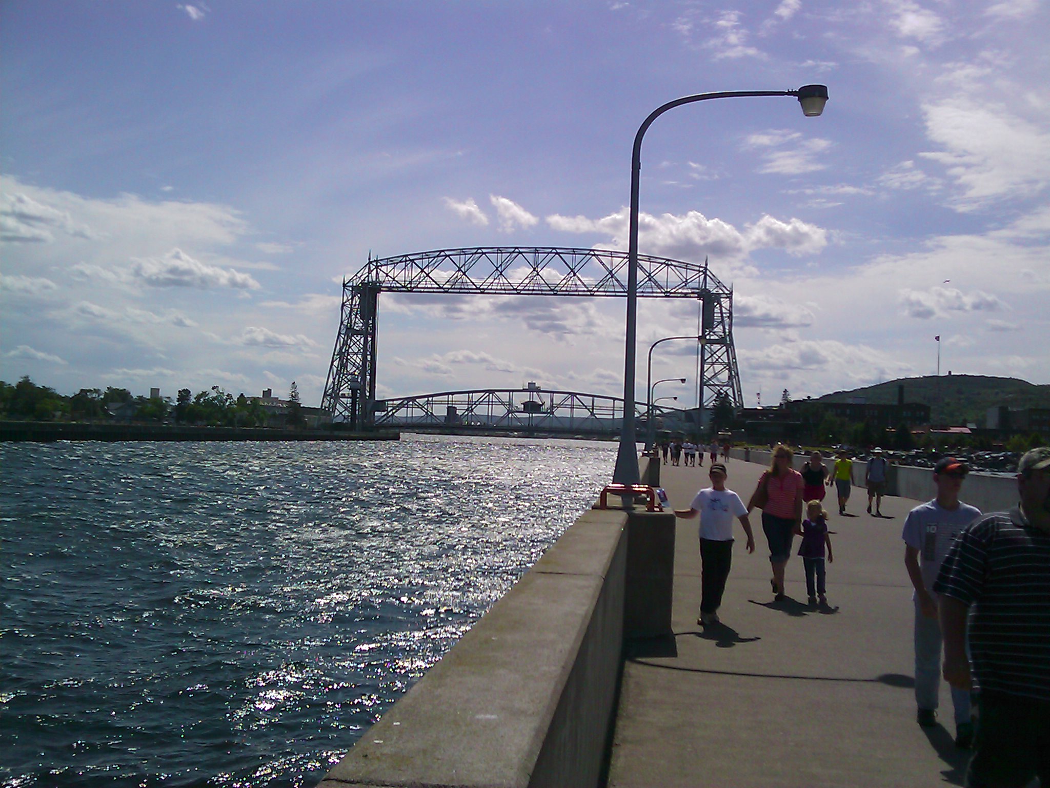 people walking on pier beside large body of water