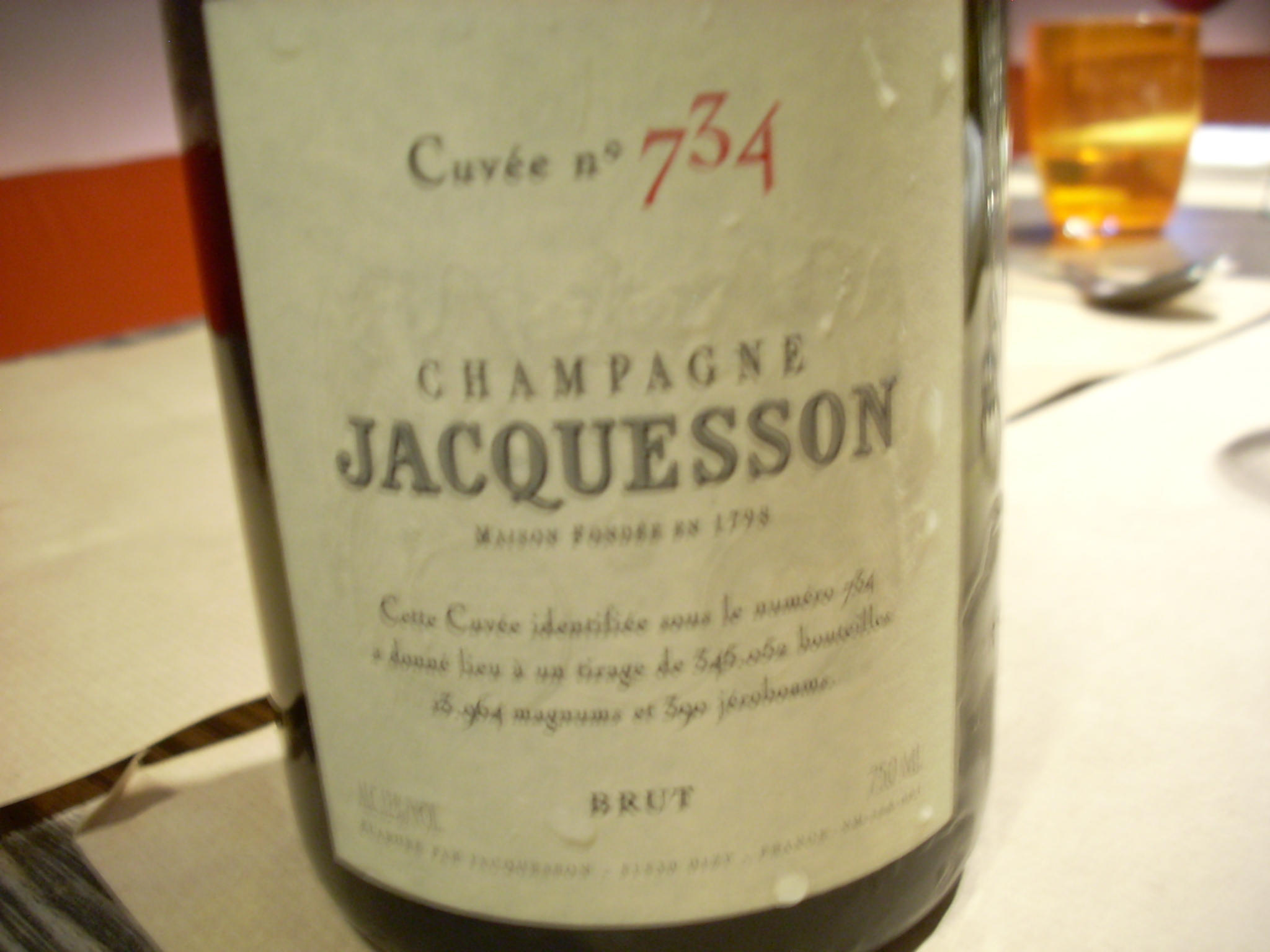 a glass with wine in it and the label is labeled champagne de jacquesson
