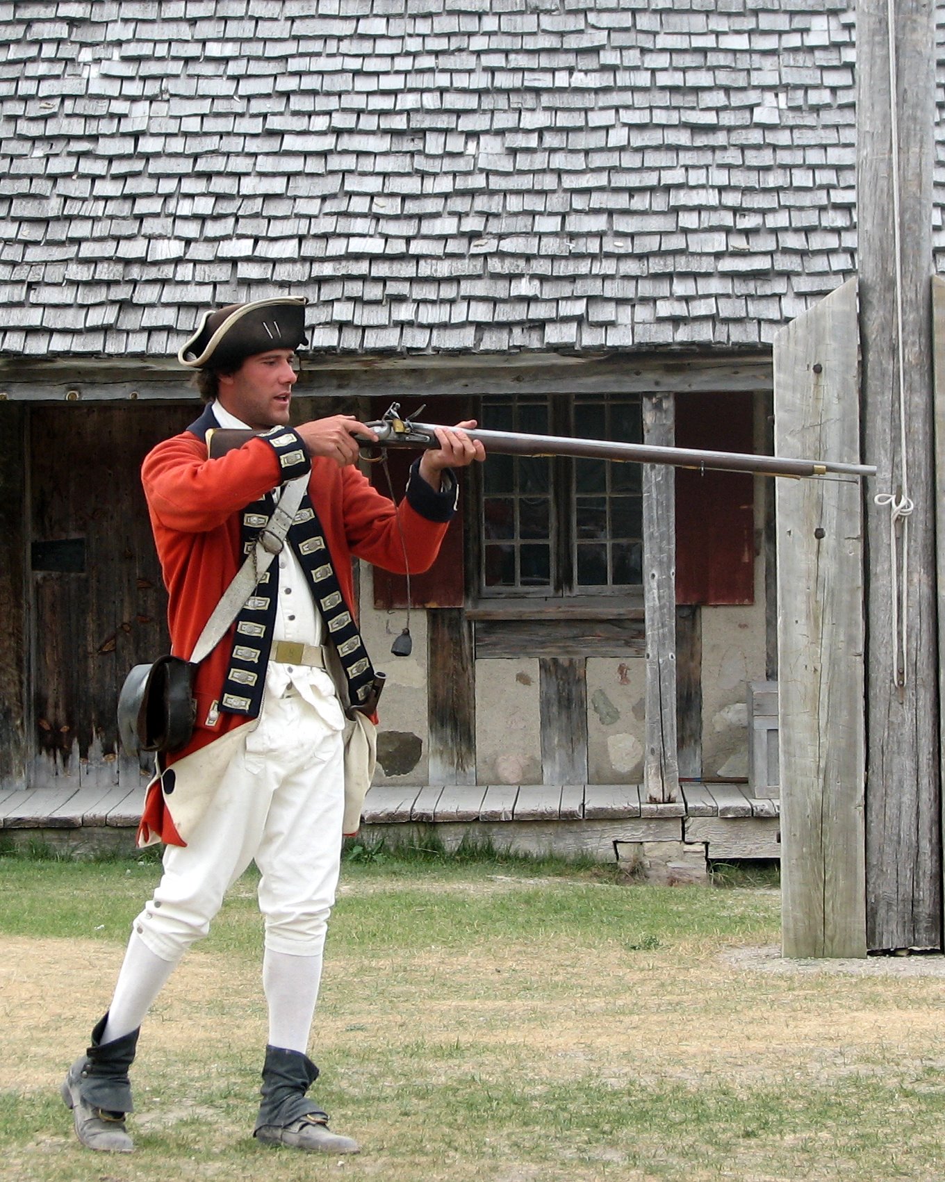 a man in an old time period costume is holding a gun with a large hat