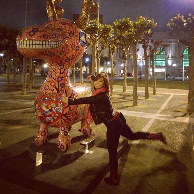 a woman posing in front of a statue of a dragon