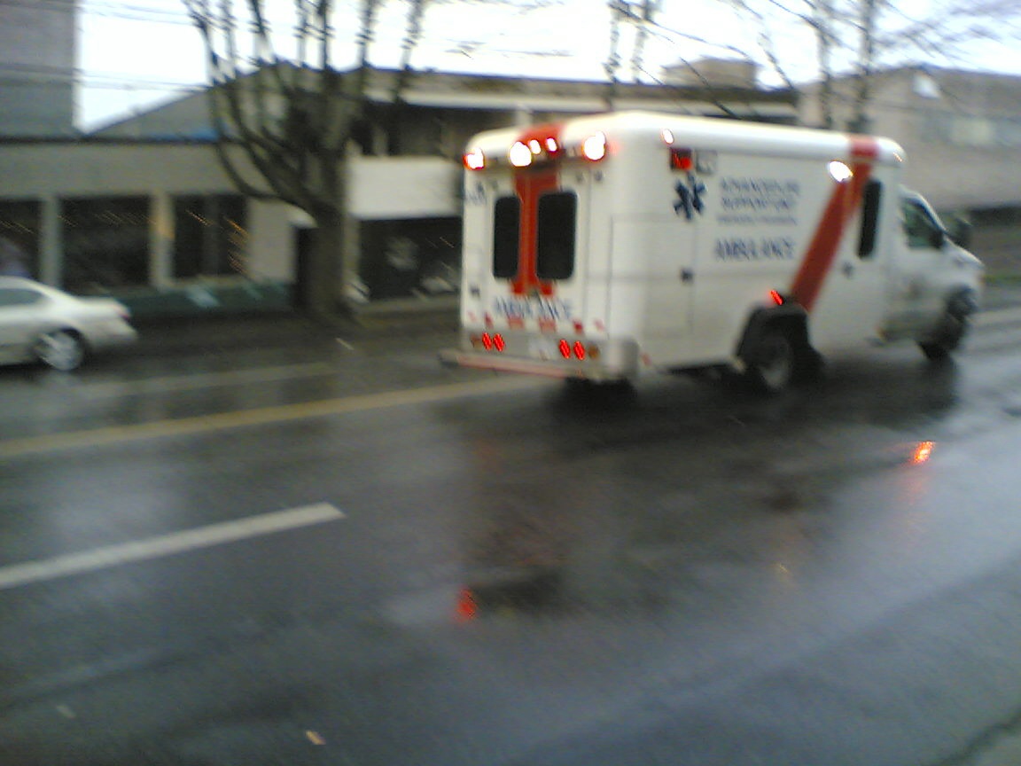 a ambulance driving down a road in the rain