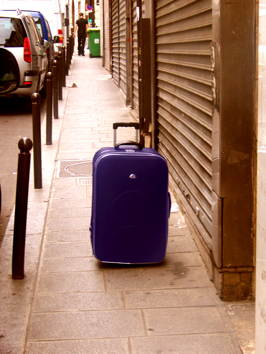 an empty purple suitcase outside a building